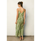 Woman wearing a sage and cream leaf patterned maxi dress against a plain background