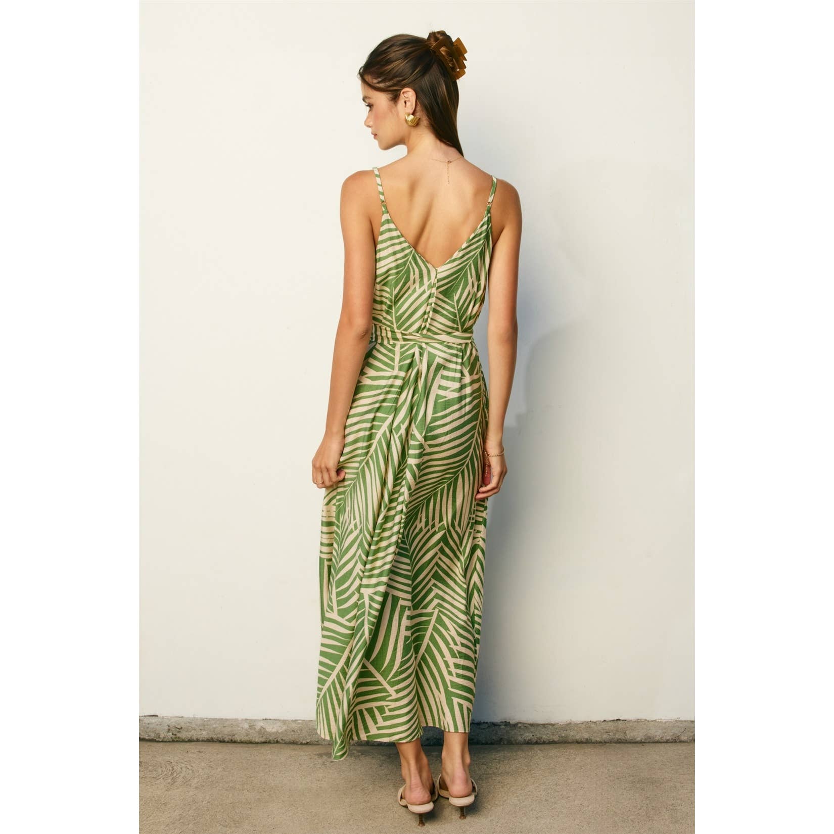 Woman wearing a sage and cream leaf patterned maxi dress against a plain background
