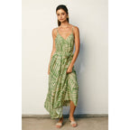 Woman wearing a sage and cream leaf patterned maxi dress against a plain background