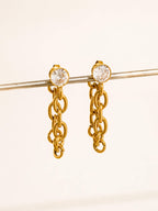Gold chain earrings with CZ stud on a beige background