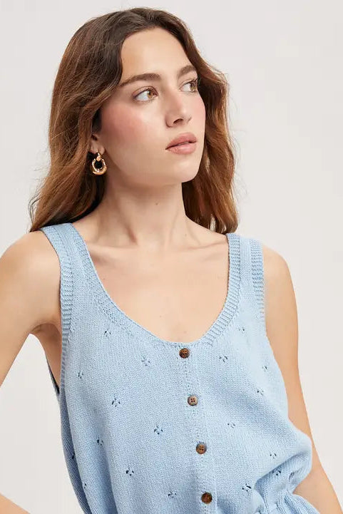 Woman wearing a sky blue sleeveless knitted tank top with buttons on a plain background