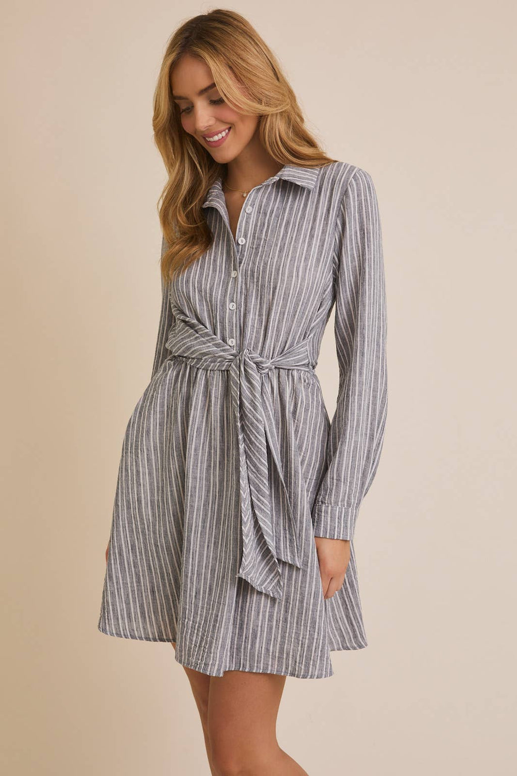 Woman wearing a striped shirt dress with a beige background