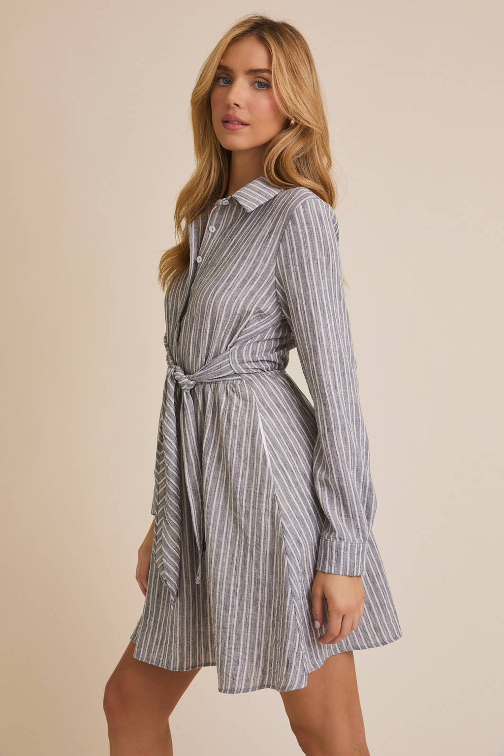 Woman wearing a striped shirt dress against a beige background