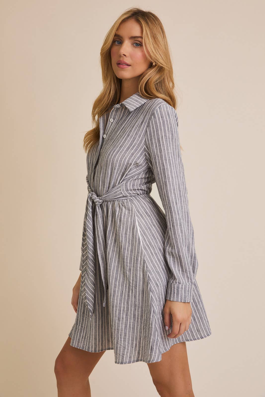 Woman wearing a striped shirt dress against a beige background