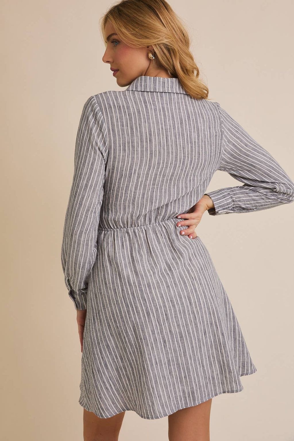 Woman wearing a striped shirt dress against a beige background