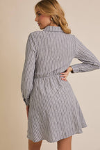 Woman wearing a striped shirt dress against a beige background
