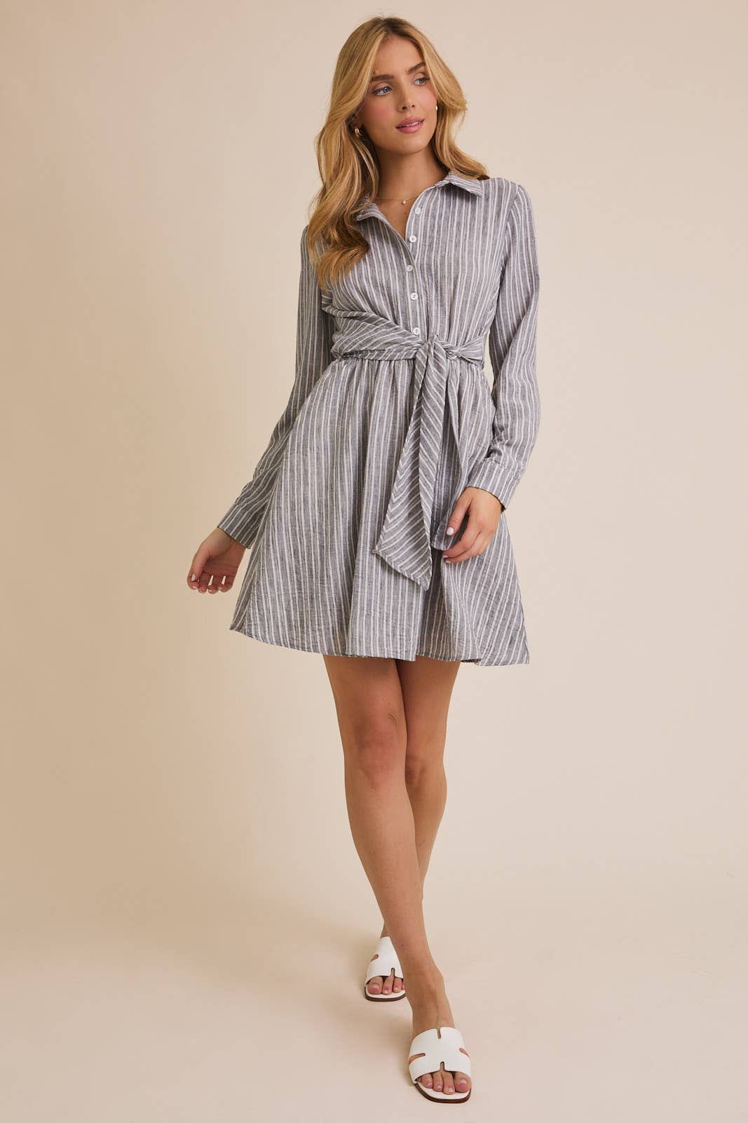 Woman wearing a striped shirt dress against a beige background