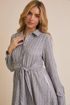 Woman wearing a blue and white striped shirt dress against a beige background