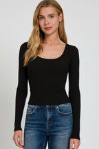 Woman wearing a black long-sleeve top and blue jeans on a white background