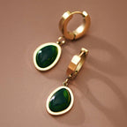 Gold hoop earrings with green gemstones on a brown background