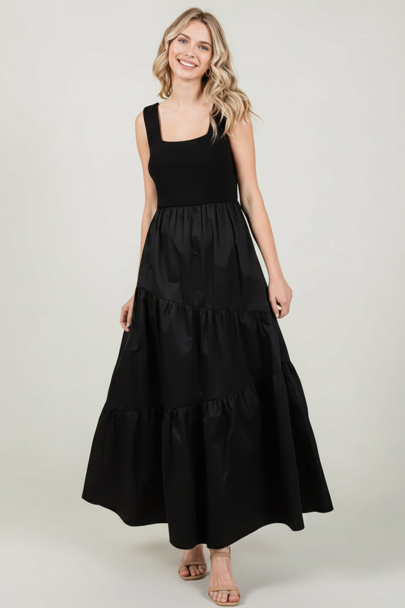 Woman wearing a black knit sleeveless tank maxi dress with poplin asymmetrical tiered skirt on a white background
