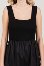 Close up of a woman wearing a black knit sleeveless tank maxi dress poplin skirt on a white background