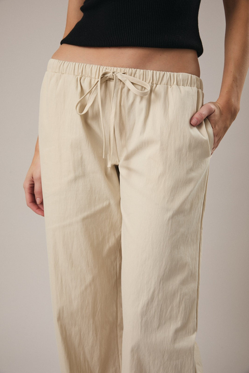 Woman wearing straight leg ecru drawstring pants against a grey background