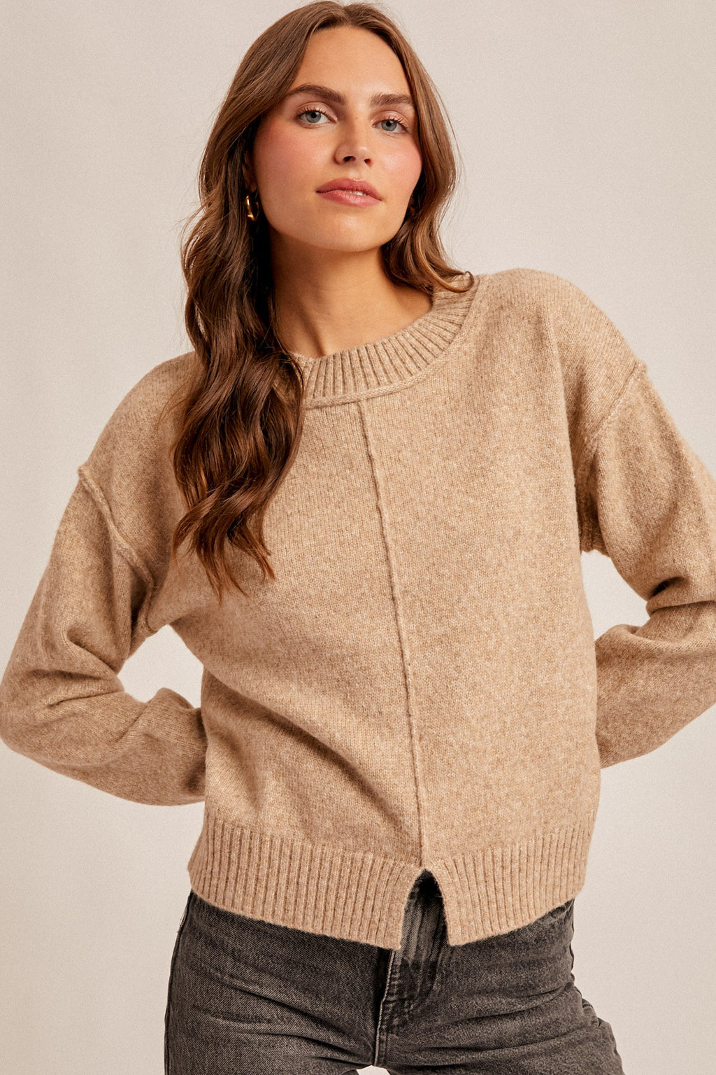 Woman wearing a tan sweater against a plain background