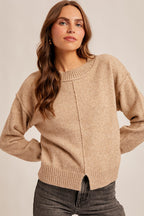 Woman wearing a tan sweater against a plain background