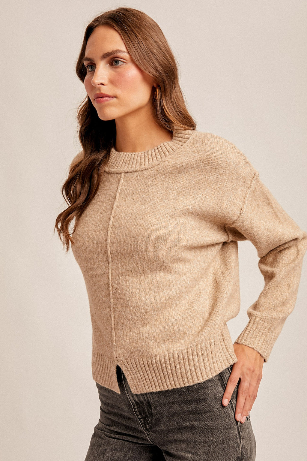 Woman wearing a tan sweater against a plain background