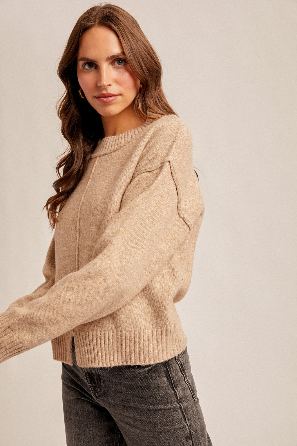Woman wearing a tan sweater against a plain background
