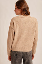 Woman wearing a tan sweater against a plain background