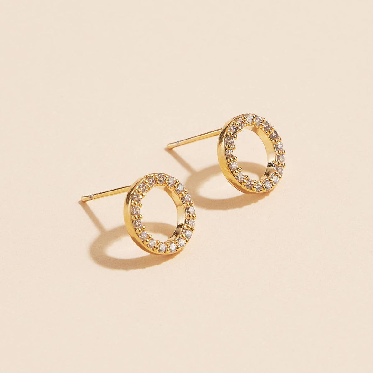 Open circle pave cubic zirconia stud earrings on a cream background