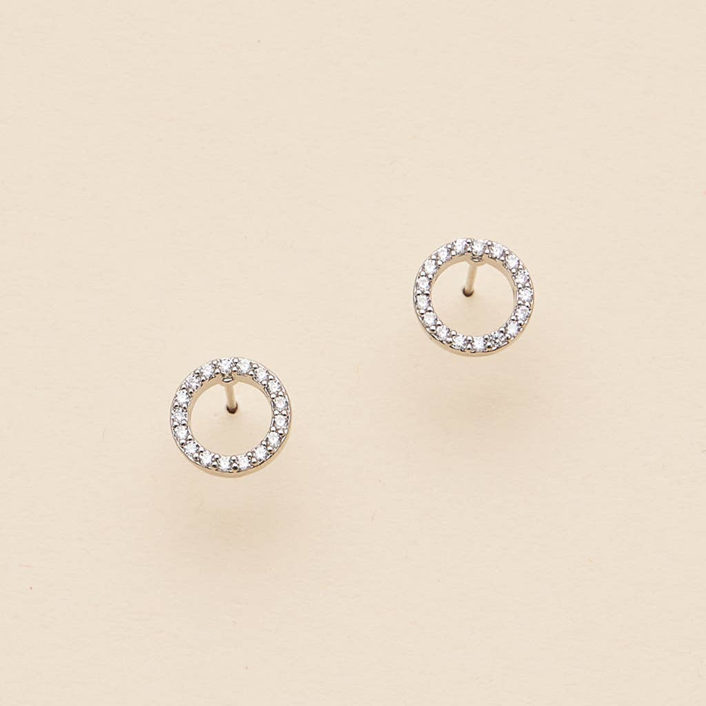 Open circle pave cubic zirconia stud earrings on a beige background