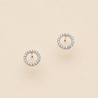 Open circle pave cubic zirconia stud earrings on a beige background