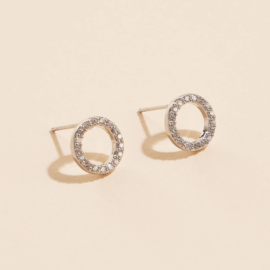 Open circle pave cubic zirconia stud earrings on a beige background