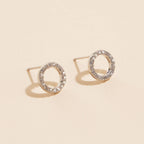 Open circle pave cubic zirconia stud earrings on a beige background