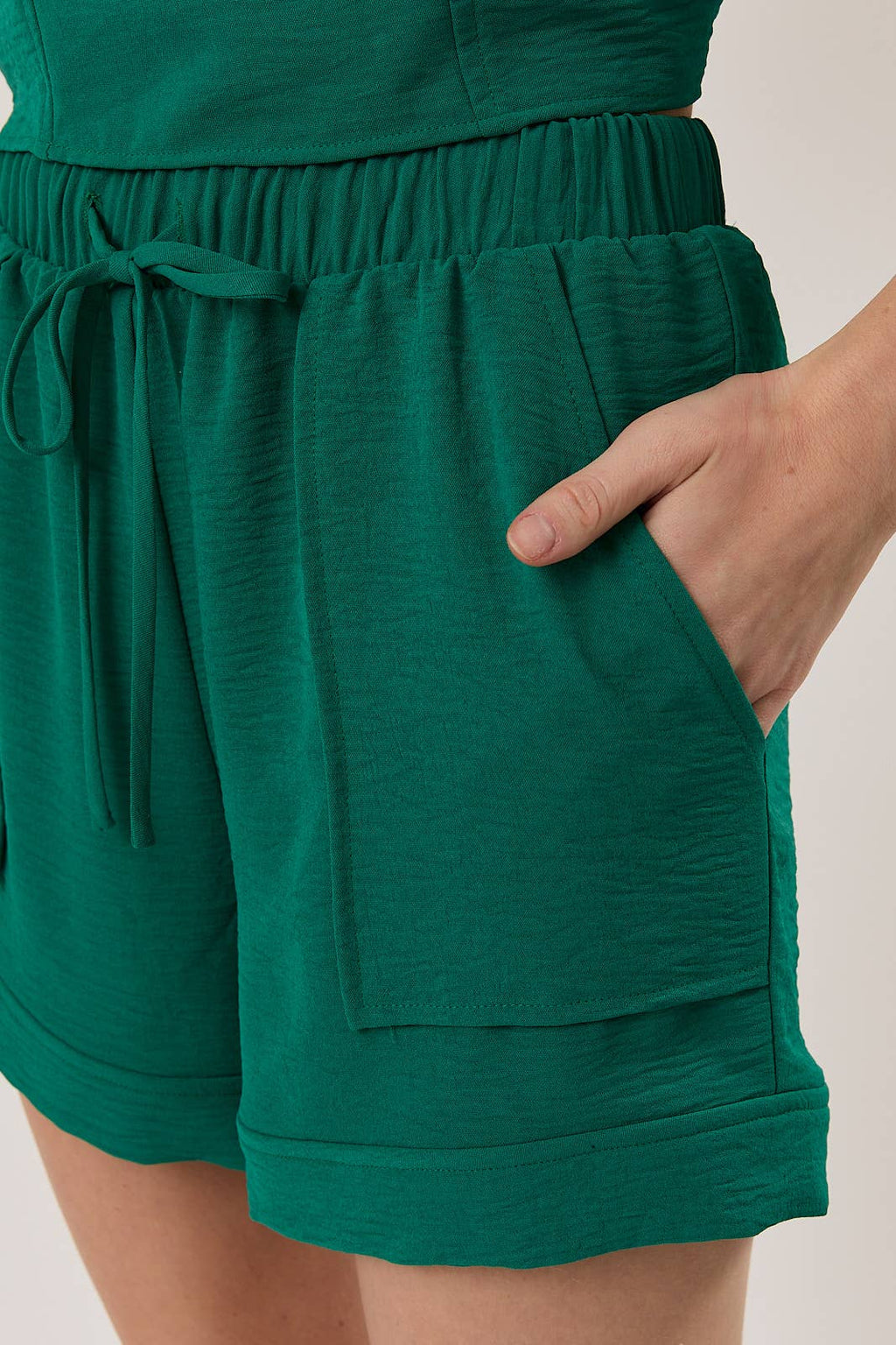 Woman wearing hunter green shorts with patch pockets against a white background