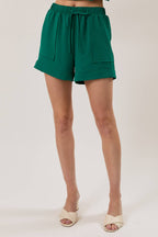 Woman wearing hunter green shorts against a white background