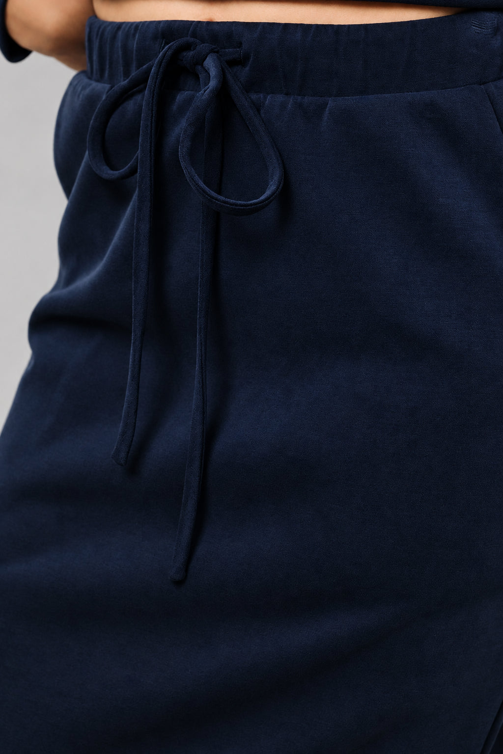 Close-up of a navy blue skirt with an elastic drawstring waistband, worn by a model.