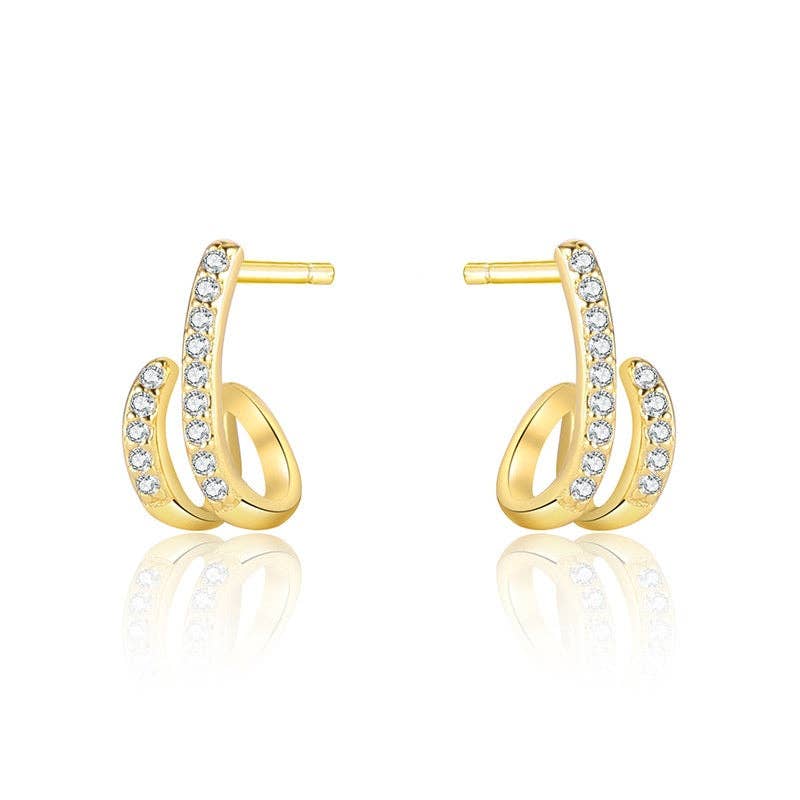 Gold-plated hoop earrings with pave CZ stones on a beige surface