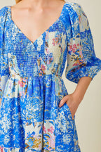 Woman wearing blue patchwork print maxi dress against grey background