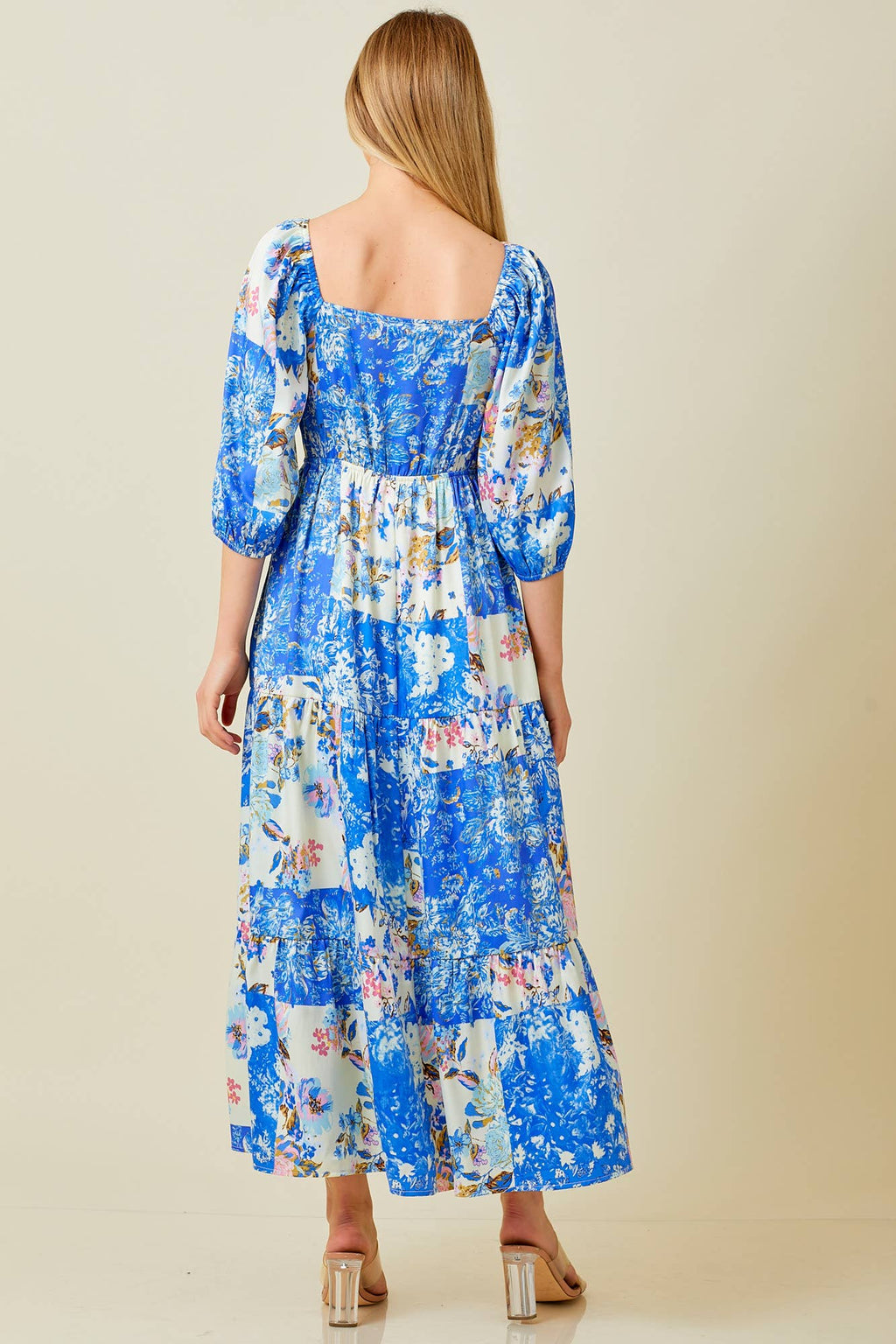 Woman wearing blue patchwork print maxi dress against grey background