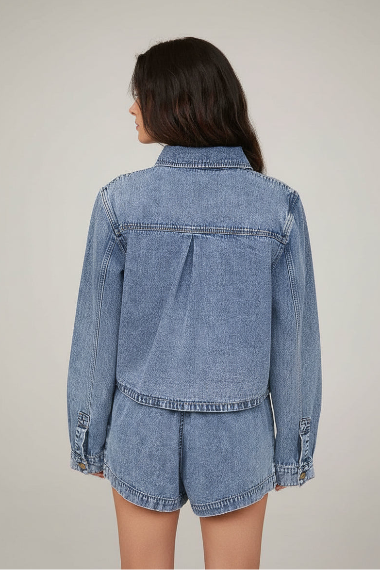 Woman wearing a denim jacket and shorts against a neutral background