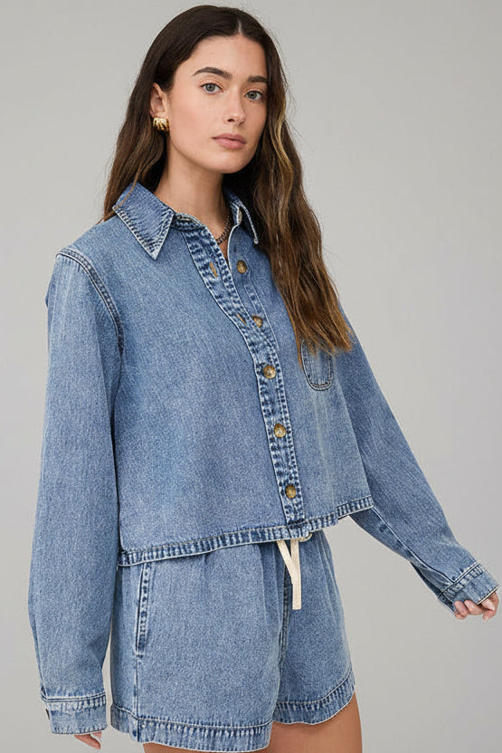 Woman wearing a denim jacket and shorts against a neutral background