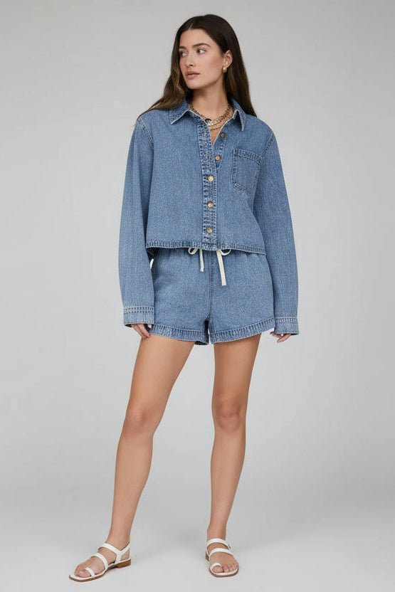 Woman wearing a denim jacket and shorts against a neutral background