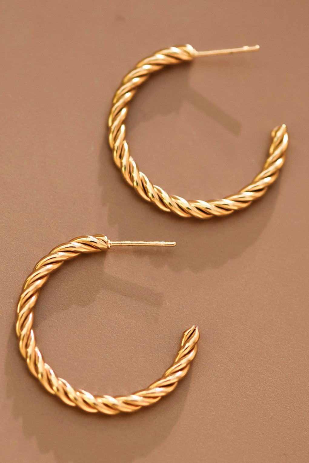 18k gold-plated stainless steel twisted hoop earrings on a brown background