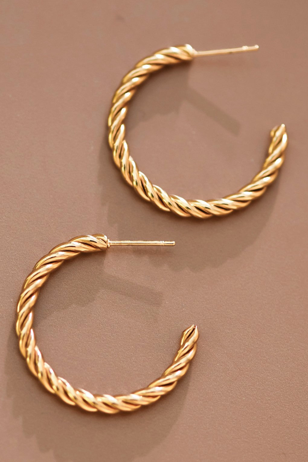 18k gold-plated stainless steel twisted hoop earrings on a brown background