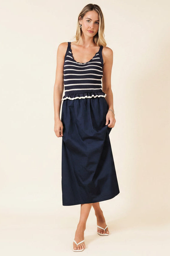 Woman wearing a navy and white crochet striped top with a navy skirt on a beige background