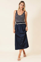 Woman wearing a navy and white crochet striped top with a navy skirt on a beige background