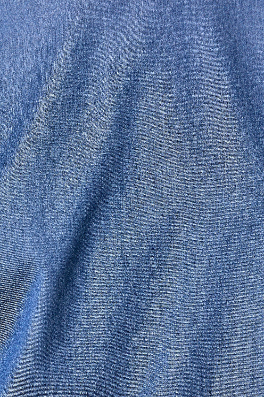 A close-up of blue denim look fabric with a visible woven texture and soft folds.