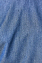 A close-up of blue denim look fabric with a visible woven texture and soft folds.