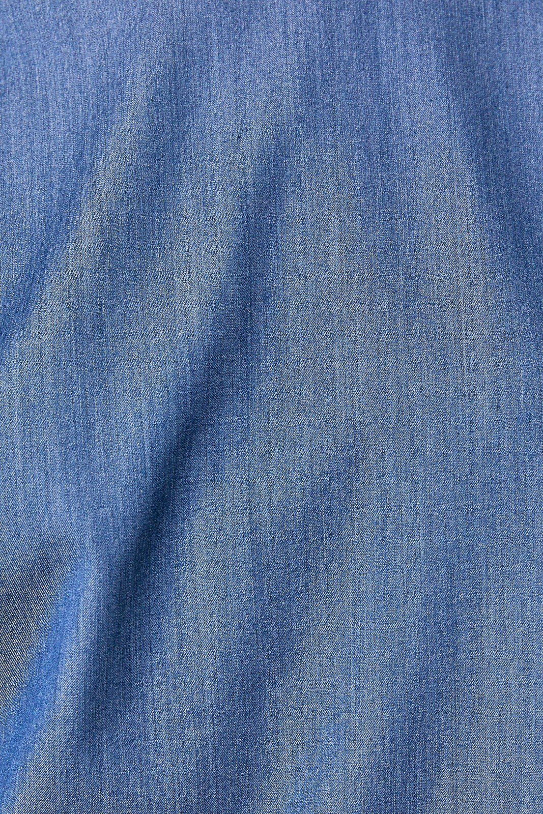 A close-up of blue denim look fabric with a visible woven texture and soft folds.