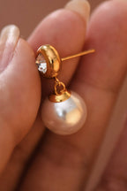 Hand holding a pearl drop earring with CZ gold stud post