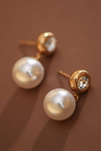 Pearl drop earrings with CZ gold stud post on a brown background