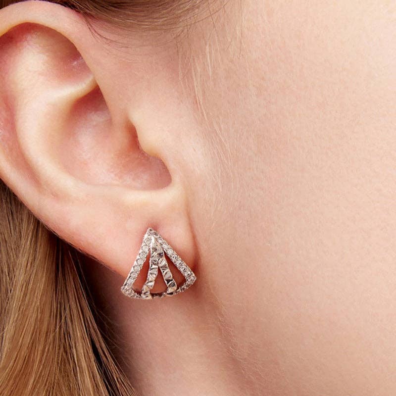 Woman wearing a pair of silver plated geometric triangle stud earrings adorned with cubic zirconia 