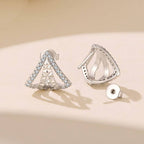 A pair of silver plated geometric triangle stud earrings adorned with cubic zirconia displayed on a warm beige surface with soft shadows.