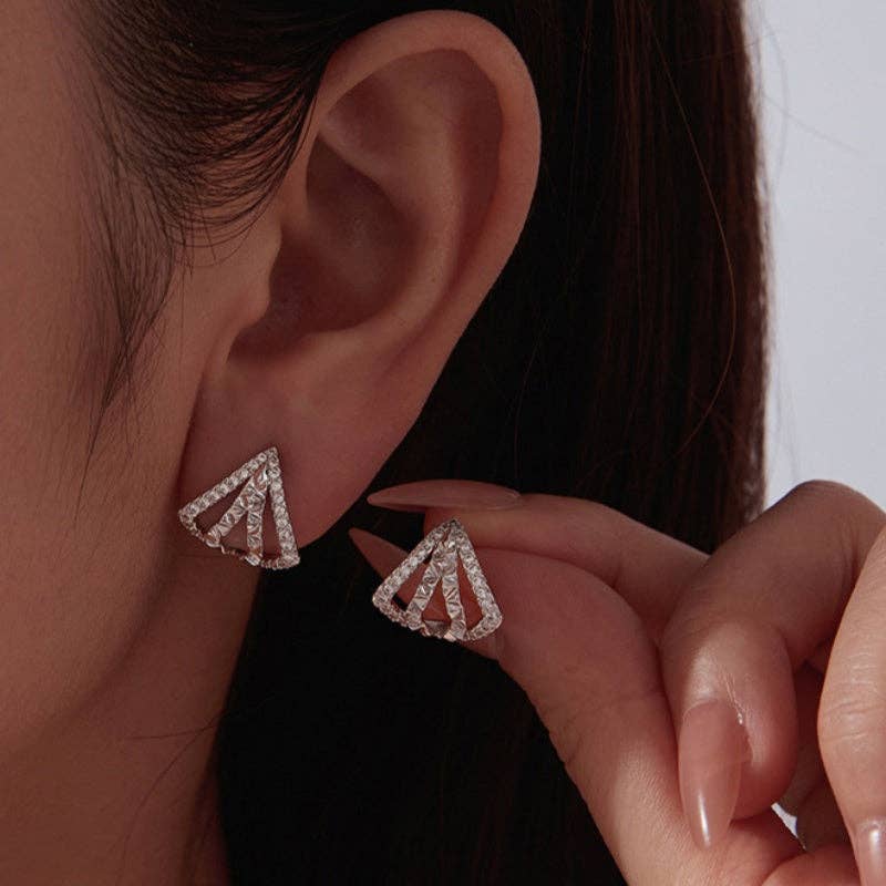 Woman wearing a pair of silver plated geometric triangle stud earrings adorned with cubic zirconia