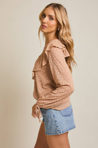 Woman wearing a taupe ruffled blouse and denim shorts on a beige background