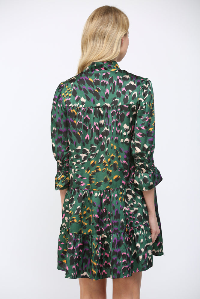 Back view of a woman wearing a green background  patterned dress on a white background